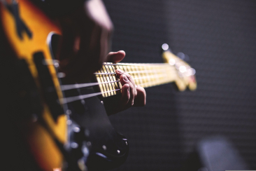 Nahaufnahme einer Hand auf dem Griffbrett eines E-Basses während eines Musikkonzerts