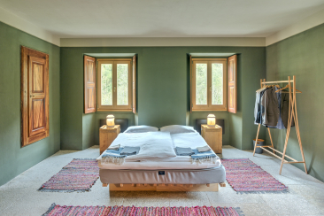 A stylishly furnished guest room at the Pontisella Bed and Breakfast in Stampa, with sage-green walls, natural stone flooring and a double bed
