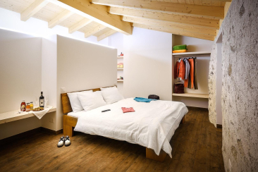 Chambre à coucher lumineuse avec plafond à poutres apparentes et lit double à l'Agriturismo Coltiviamo Sogni à Campascio