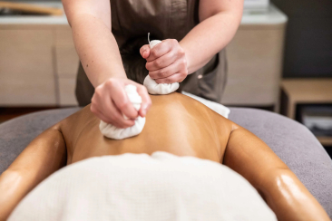 Soin du dos avec des pochons d'herbes chauds lors d'un massage au Spa Saoseo